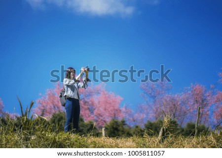 A portrait of a young woman holding a camera in the park and blue sky background