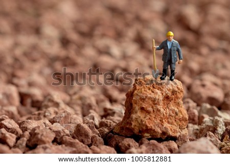 Laborer concept : Miniature worker standing on stone with swarm. Picture use for Mining business or Department of Mineral Resources. (DMR)