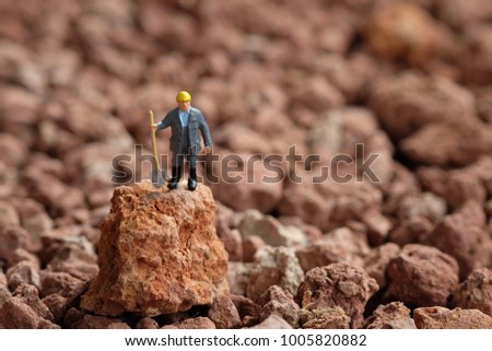 Laborer concept : Miniature worker digging on stone . Picture use for Mining business or Department of Mineral Resources. (DMR)