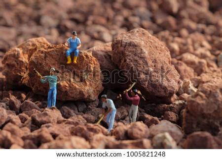 Laborer concept : Miniature worker digging on stone . Picture use for Mining business or Department of Mineral Resources. (DMR)