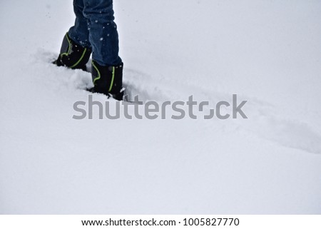 Wearing snow boots walking up hill in the snow feet legs only