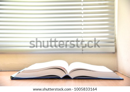 The book is opened on white background with the window blind, in concept of education, self study, readying corner