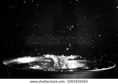 Black and White water droplet splash in metallic bowl with black background