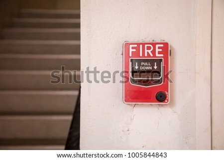 The hand is pulling fire alarm signal on the wall next to the door 