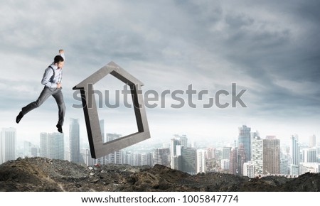 Jumping businessman crashing big house symbol with city view on background. 3D rendering.
