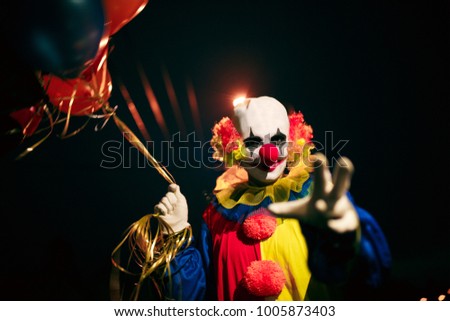 Picture of smiling clown with balls in hands at night