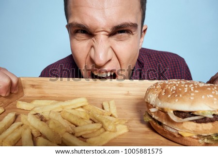   hungry man with a tray of fast food on a blue background                             