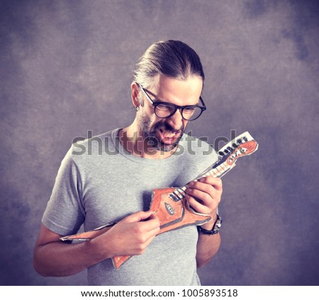 wild young man with cardboard guitar in front of gray background