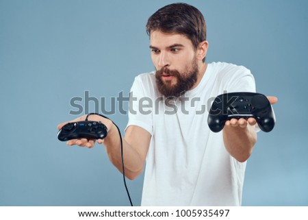  man with a beard holds a joystick on a blue background                              