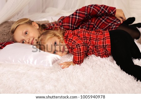 holiday photo of two beautiful girls sisters with blond hair having fun together