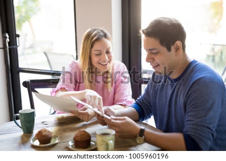 Portrait of a happy young couple reading menu card and deciding what to order while hanging out in a restaurant