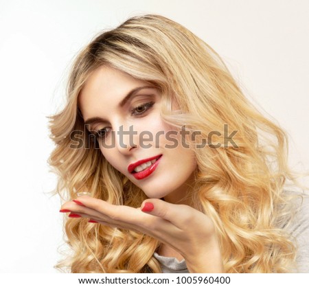 A transparent contact lens in the hands of a beautiful blonde who is preparing to insert it.