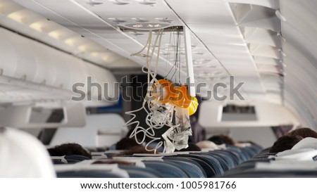 Oxygen Mask falling out in Airplane. Royalty-Free Stock Photo #1005981766
