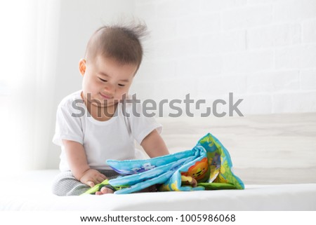Asian baby boy sitting and reading cartoon, 5 month old