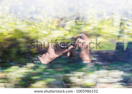 Blur traveler photographer  hold camera reflect on high speed train window while running with nature forest background.