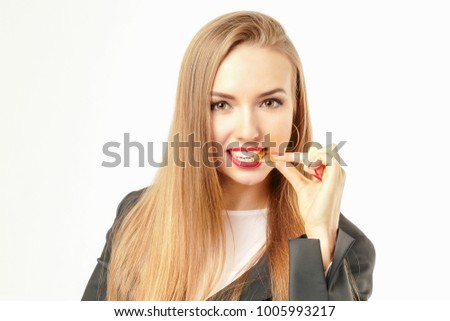 Pretty woman tasting a golden bitcoin coin on her tooth.