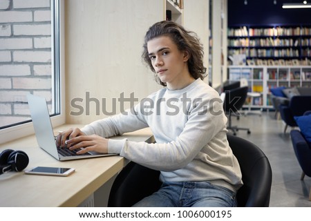 Picture of creative young male copywriter focused on distant work, creating new article for online blog, typing on keyboard of modern laptop computer. People, technology, occupation and job concept