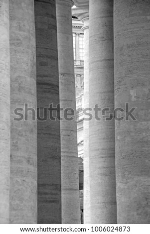 Fragment of the St. Peter's Basilica (Basilica di San Pietro) is visible through the massive columns in Vatican City, Italy. Black and white photography