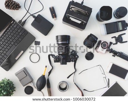 top view of photographer concept with digital camera, battery charger camera, memory card storage box, external harddisk, flash, computer laptop, notebook and camera accessory on white background. 