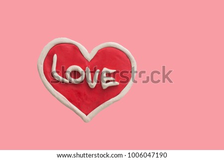 Red heart with the word Love made from plasticine isolated on a pink background