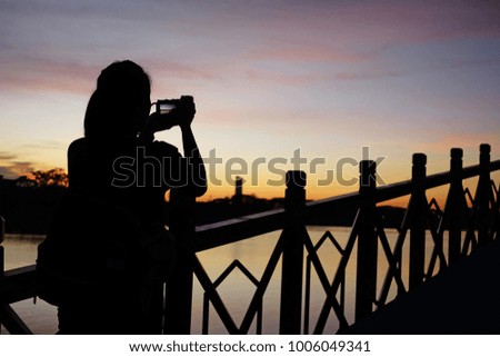 Silhouette of woman taking photo with beautiful sunset