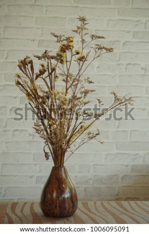 Bouqet of dry flower in woodden vase put on the table and white  concrete background