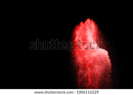 Red particles explosion on black background. Freeze motion of red dust splash on dark background.