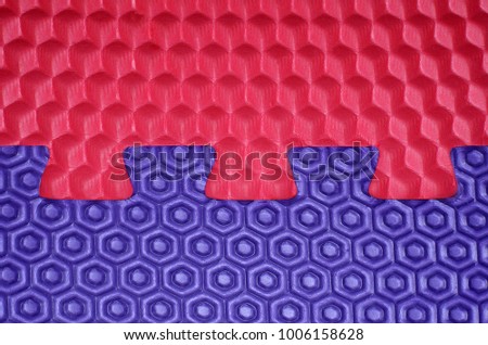 Two pieces of puzzles - blue and red with different geometric seamless shapes pattern.Close-up. Puzzle Color Rubber Floor. Colorful texture.