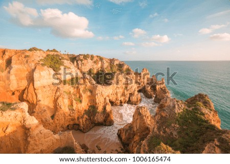 beautiful Atlantic ocean view horizon with sandy beach, rocks and waves at sunrise. Algarve, Portugal