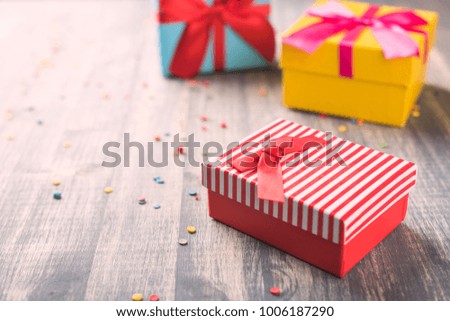 Red gift boxes on wooden background.  Striped, yellow and blue boxes with ribbon on table. Vintage and retro toned