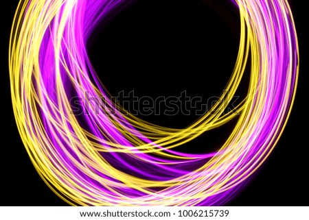 Pink and gold light painting photography, wavy stream of colorful light against a black background