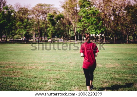 a young Asian woman with pony tail hair prepare her body before a daily exercise activity, running or jogging, by stretching her body and legs at the park in the middle of the city in a summer morning