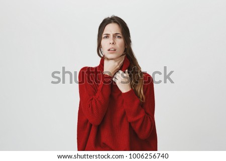 Attractive european woman in stylish red sweater having sore throat feeling pain after catching cold, isolated over white background. Health Care concept. Student should immediately visit doctor. Royalty-Free Stock Photo #1006256740