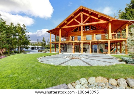 Beautiful American classic log cabin with porch and circle fire pit.