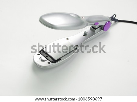A hair iron for silver color on a white background. Hair care.