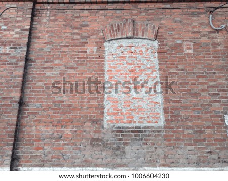 red brick wall with a blocked window