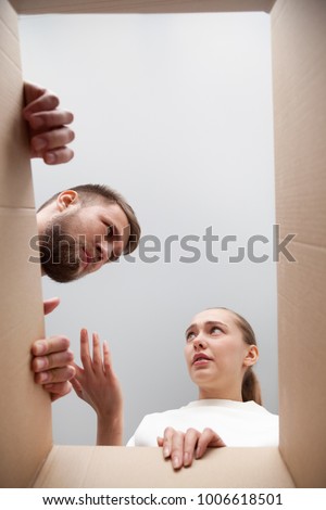 Confused customers dissatisfied with damaged broken parcel, angry couple disappointed after dispatching cardboard box with wrong order, bad delivery service and refunding concept, view from open box Royalty-Free Stock Photo #1006618501