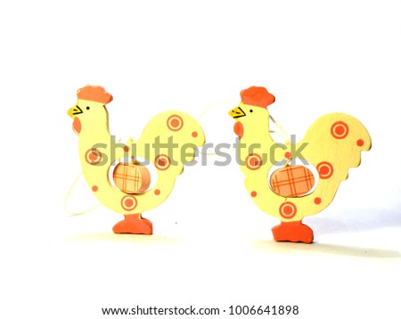 Two easter hen decorations with eggs in their stomachs in a line isolated against a white background, white and pink, facing same direction 