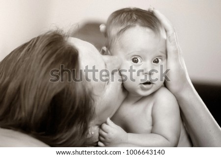 Black and white portrait of a mother kissing her little daughter