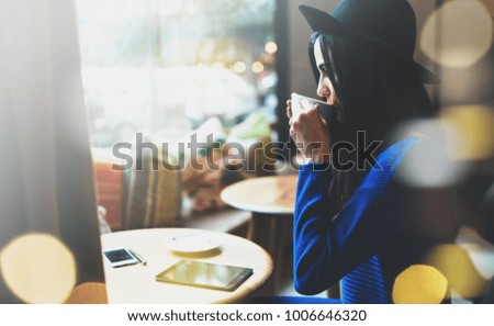 an attractive brunette young business woman enjoys a morning coffee in a coffee shop before the start of the work day. coffee break. modern gadgets on the table.bokeh light. Film effects