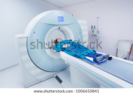 Female patient undergoing CT - Computerized Tomography Scan in Hospital. Patient wearing lead apron to   cover vital organs. Royalty-Free Stock Photo #1006650841