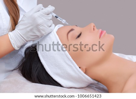 The doctor cosmetologist makes the Rejuvenating facial injections procedure for tightening and smoothing wrinkles on the face skin of a beautiful, young woman in a beauty salon.Cosmetology skin care. Royalty-Free Stock Photo #1006651423