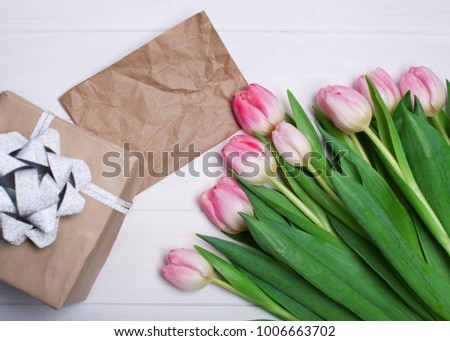 Pink tulips on a white wooden background with a gift and copy space for writing