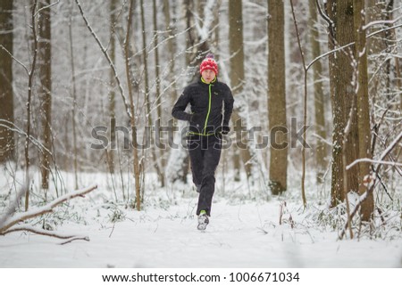 Photo of running athlete among trees in winter forest