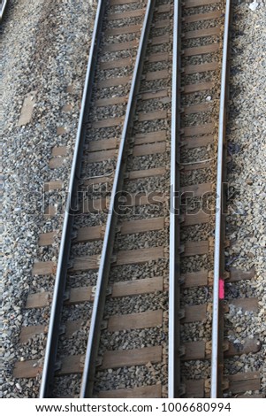 Close up view from above of a pair of rails. Leading parallel steel rails with regular crossbars. Pattern composed by the different lines and texture underlined by the gravel. Abstract geometric view.