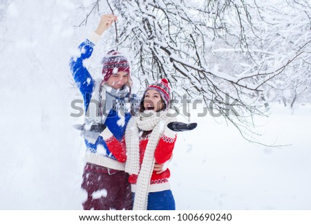 Couple shaking a tree branch with snow in winter forest