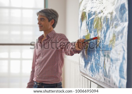 Teacher explaining geographic map in a classroom. Royalty-Free Stock Photo #1006695094