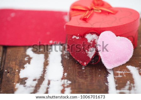 Red heart box on wooden background. Beautiful romantic vintage red heart on a white snow winter background.