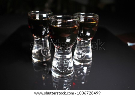 Rum shots. Alcohol shot brown dark rum on black reflective studio background. Isolated black shiny mirror mirrored background for every concept.