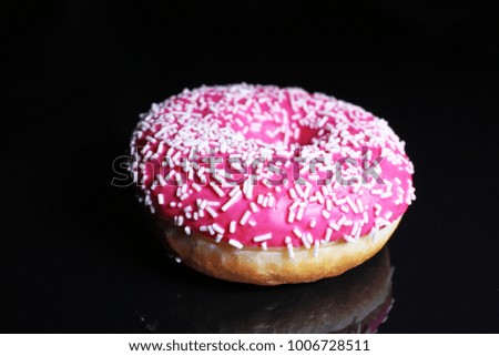 Donut. Beautiful pink donut on black reflective studio background. Isolated black shiny mirror mirrored background for every concept.